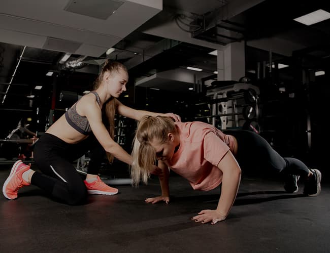 Coach guiding a client through press-up technique while training together